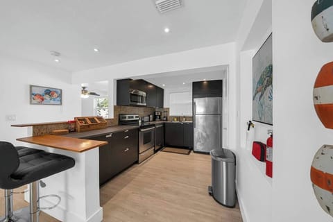 Fully equipped kitchen with a full refrigerator, stove top, oven, and utensils