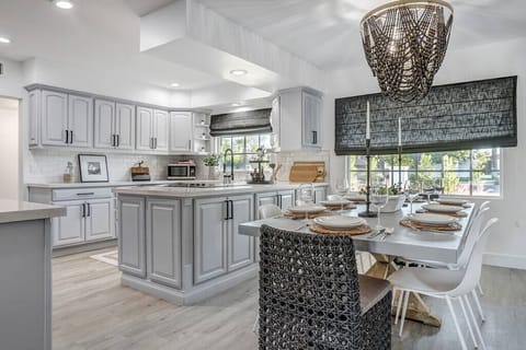 Modern kitchen and dining area with a large island and natural light from windows.