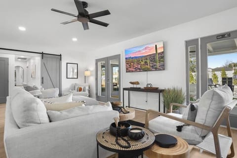 Modern living room with neutral tones and natural light from large windows.