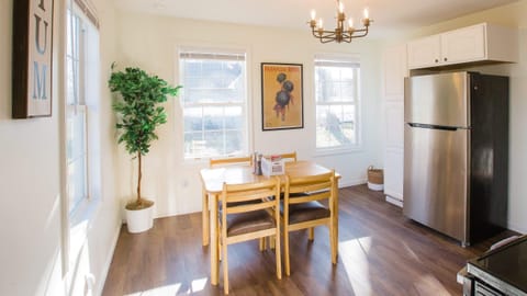 Spacious dining area viewed from kitchen and back bedroom doorway. Large stainless steel refrigerator/freezer in kitchen