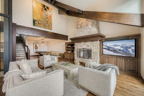 Gather around your cozy stone fireplace in this elegant living room, where mountain views and exposed beams create the perfect alpine retreat atmosphere.