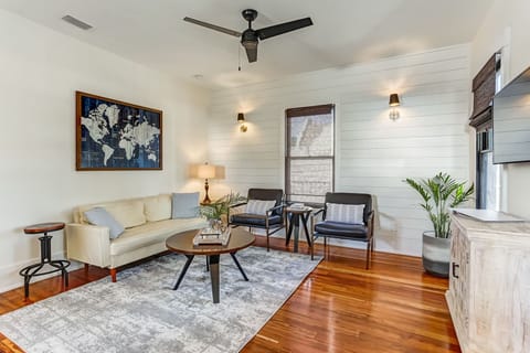 - Relax in this bright lounge featuring a comfy cream sofa, two sleek armchairs, and a stylish world map wall piece
- Warm hardwood floors and a neutral area rug create a cozy yet modern vibe
- Ceiling fan, natural light, and greenery complete the space