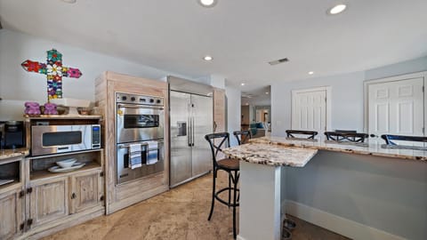 Gourmet kitchen with Viking appliances, a double oven, a large refrigerator, and a breakfast bar with granite countertops.