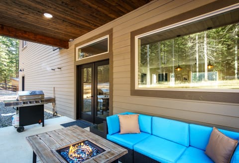 Covered backyard patio with propane fire table and four burner propane grill.