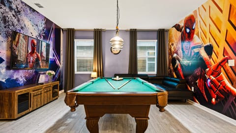 Vibrant game room with a pool table, large TV, cozy seating, and superhero decor!