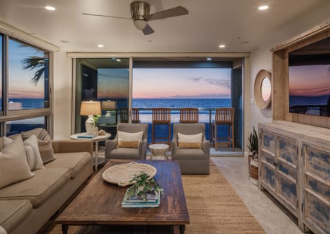 Luxurious contemporary living space with rustic accents and expansive windows showcasing stunning oceanfront views.