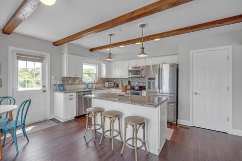 - Kitchen island includes three stools and elegant pendant lights above
- Stainless appliances and white cabinetry create a modern yet beachy feel
- Perfect for cooking, sipping wine, or prepping snacks before beach outings