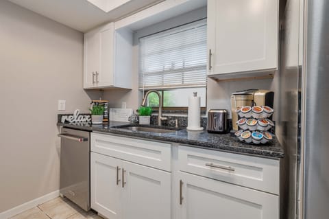Stainless steal KitchenAid dishwasher. Kitchen sink window view of backyard.