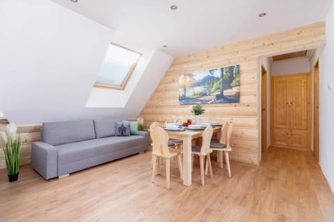 A cozy attic-style living area with wooden paneling and a dining table.
