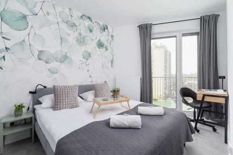 A cozy bedroom with floral wallpaper, a comfortable double bed, and a modern design.
