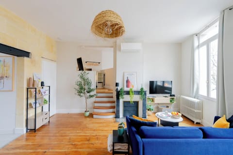 Sunny living room with chic décor, blue sofa, TV, and cozy fireplace
