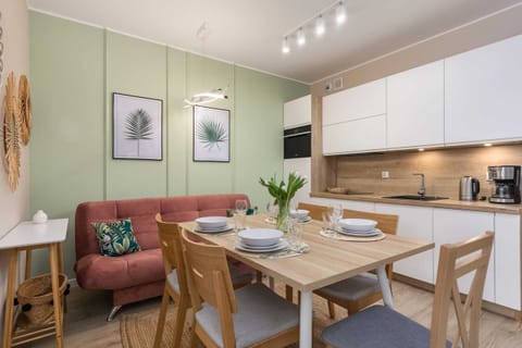 A dining area with a pink upholstered bench and a light wood table set for a meal.
