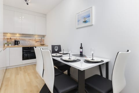 Dining area with a table set for four, featuring a clean, minimalist aesthetic and soft lighting.