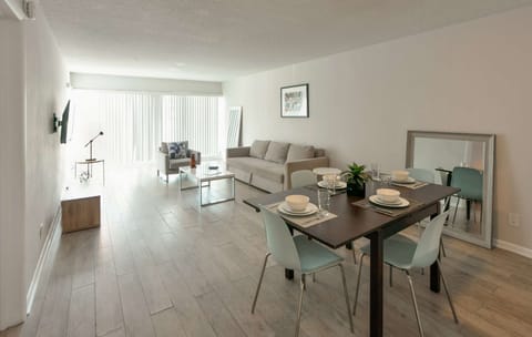 Bright living and dining space with sofa, chairs, and wide window