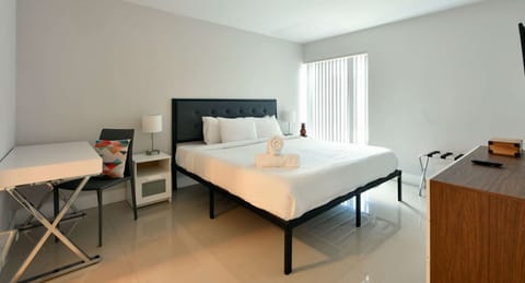 Bright king bedroom with desk, dresser, and window blinds