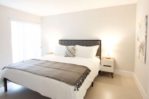Bright king bedroom with side table, lamp, and wall art