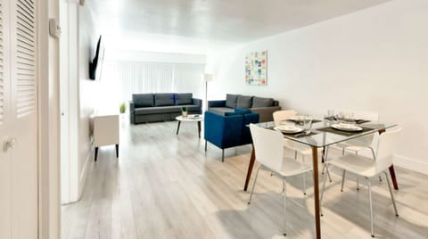 Open living and dining area with sofa, chairs, and glass table