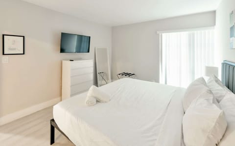 Bedroom with wall TV, dresser, mirror, and luggage rack