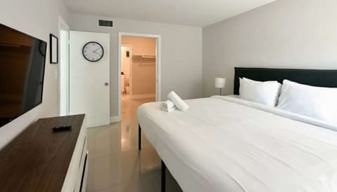 King bedroom with wall TV, dresser, and open bathroom doorway