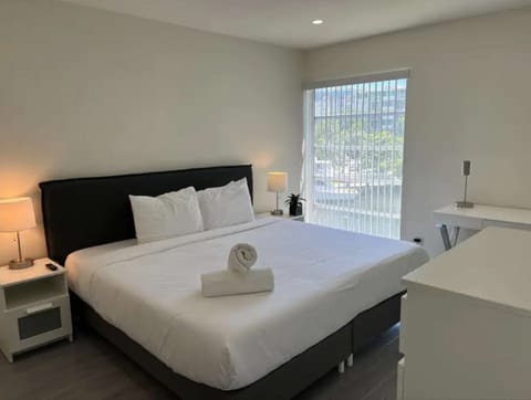 Bright king bedroom with desk, dresser, lamps, and window