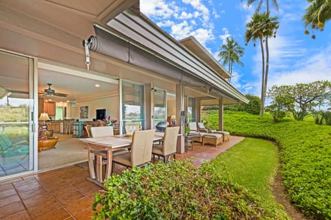 Enjoy al fresco dining and relaxation on this private lanai, complete with comfortable seating, a dining table, and stunning views of lush tropical gardens and palm trees.