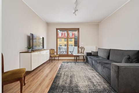 Spacious living room with a comfortable gray sofa, wooden flooring, and a modern coffee table.

