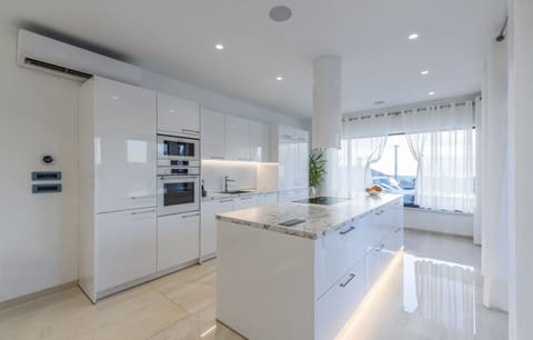 Spacious kitchen decorated in white with a large kitchen island illuminated by LED light