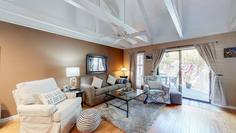 This inviting living area features vaulted, beam-accented ceilings and warm natural light, creating an open, comfortable gathering space.