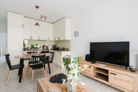 A cozy living room with modern decor, a wooden TV cabinet, and a floral arrangement on the table.

