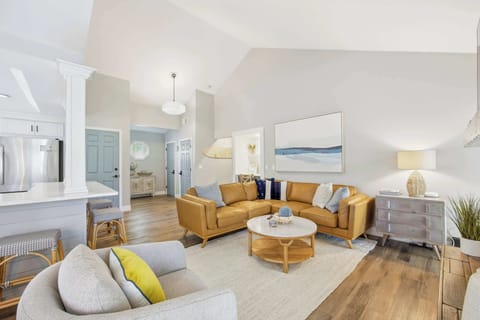 Bright living room with vaulted ceilings and a leather sectional sofa.