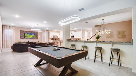 Open-concept living area with a pool table, modern kitchen, and cozy seating.