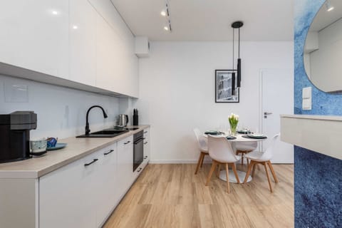 An open-plan kitchen and dining area with white cabinetry, wooden flooring, and elegant décor.
