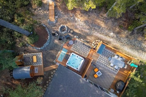 Aerial view of the backyard. We have a 6-person Barrel Sauna, a 6-person Hot tub, an outdoor shower, a Weber grill, and a little bridge that leads to a hiking trail that's about a 5 to 8-minute walk through the woods. 