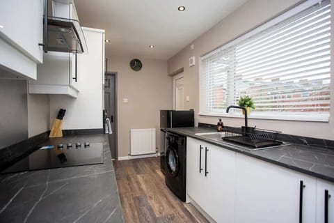 kitchen equipped with washing machine, cooker, fridge, microwave, kettle, coffee machine and toaster at the ambiance of a natural light.