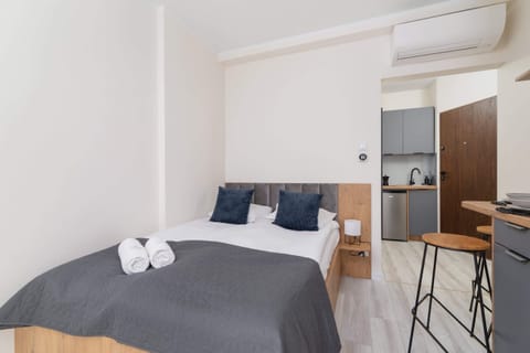 A modern bedroom with a comfortable double bed, gray bedding, and wooden accents.
