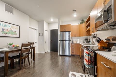 Open kitchen w/ stainless steel appliances, wood cabinets & dining table for easy meals at home.