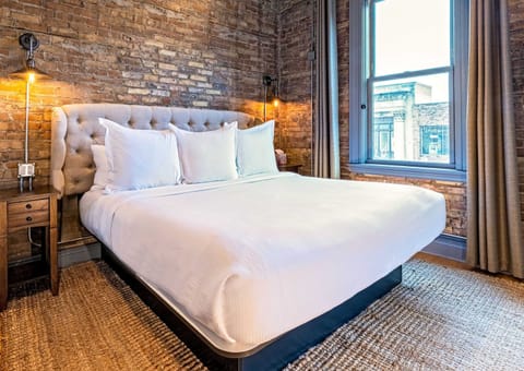 King bed, original brick, and warm industrial sconces. This is what a well-designed downtown loft actually feels like.