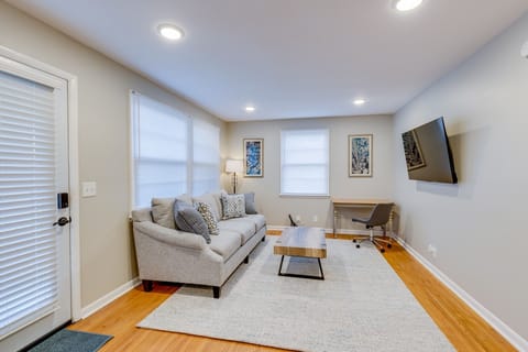 Living room with couch, coffee table writing desk and chair, lamp and 55” TV