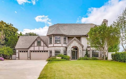 Elegant two-story home with stone accents, arched entry, and a three-car garage,