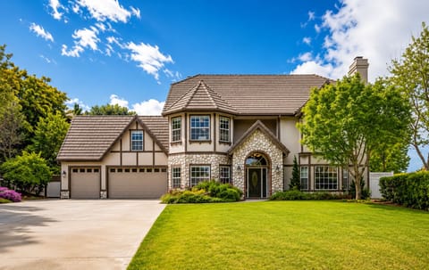 Elegant two-story home with stone accents, arched entry, and a three-car garage,