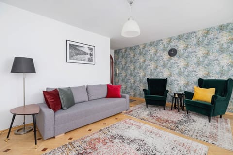 A bright living room with a gray sofa, colorful cushions, and a stylish yellow chair.
