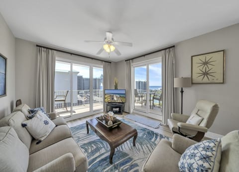 Bright corner-unit living room with dual floor-to-ceiling glass doors opening to the wraparound balcony.