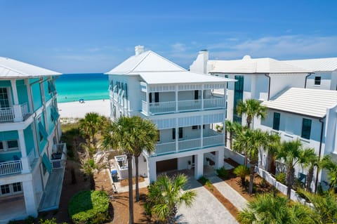 Beachfront property featuring white coastal architecture with multiple balconies and tropical landscaping, steps from pristine turquoise waters.