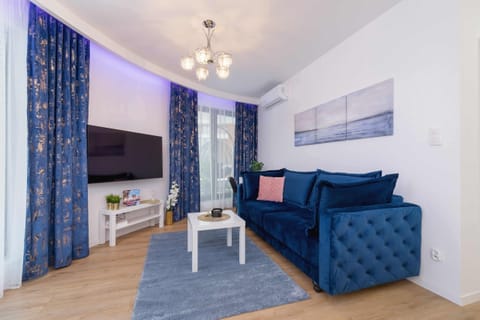 A stylish living room with blue sofas, a coffee table, and elegant blue curtains.

