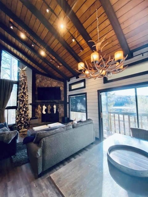 Step into a cozy mountain retreat where you can unwind by the stone fireplace and bask in the warmth of the rustic wood-beamed ceiling. The stunning chandelier and panoramic views create a perfect setting for relaxation.