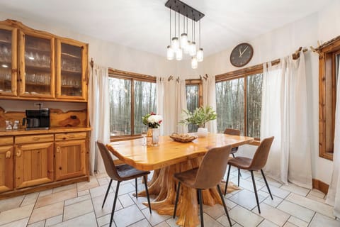 Bright dining area with a handcrafted table, surrounded by windows—an inviting spot to gather for meals and conversation.