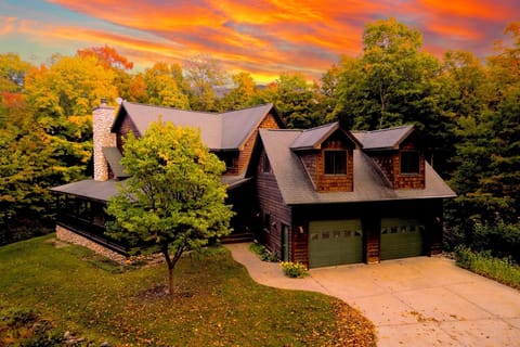 Front exterior of the home, showing the wrap-around porch, stone chimney, and attached garage.