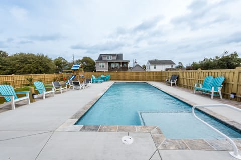 Large saltwater concrete pool with large sitting area with tables and chairs.