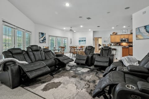 Living area with 5 reclining chairs and French doors to the covered pool area.
