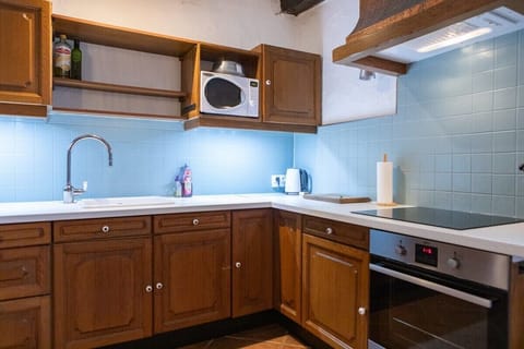 Fully equipped kitchen with microwave, oven, electric hob and a large dining table.